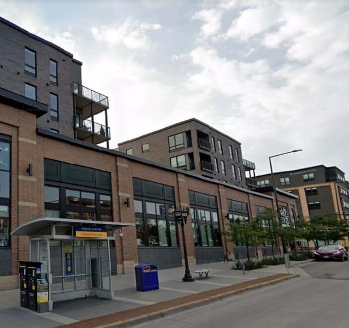 Exterior image of multi-story building with residential uses on top levels and commercial uses on the ground floor with prominent adjacent transit access.